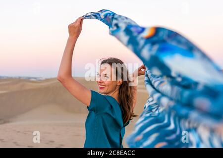 Portrait d'une femme heureuse tenant un tissu au coucher du soleil dans les dunes, Gran Canaria, Espagne Banque D'Images