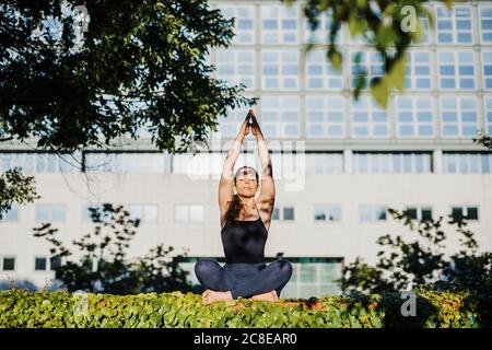 Jeune femme détendue pratiquant le yoga en position de prière tout en étant assise sur l'herbe au parc de la ville Banque D'Images