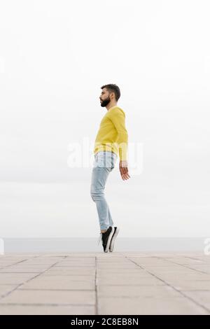 Un jeune homme dansant sur un sentier contre un mur blanc Banque D'Images