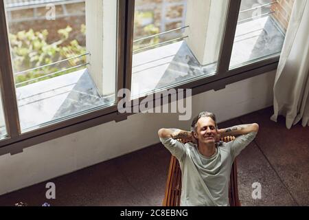 Homme senior se relaxant sur une chaise dans un appartement loft Banque D'Images