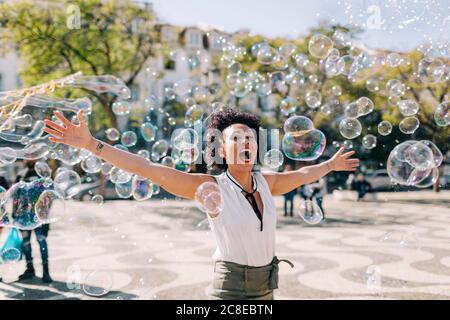 Femme adulte de taille moyenne sans souci jouant avec des bulles tout en restant debout ville Banque D'Images