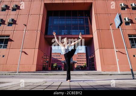 Jeune femme pratiquant le yoga à la main à la pose de gros orteil sur la rue de la ville Banque D'Images
