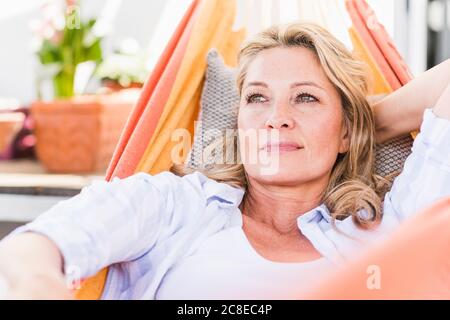 Portrait de la femme mûre pensive se relaxant dans le hamac Banque D'Images