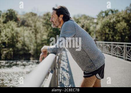 Homme mûr réfléchi regardant loin en se tenant debout près de la main passerelle Banque D'Images