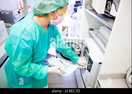 Femme dentiste stérilisant des instruments médicaux en clinique Banque D'Images