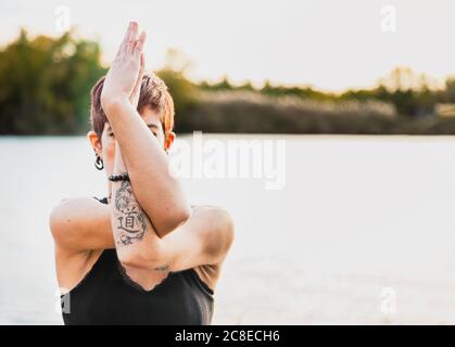 Gros plan d'une femme adulte de taille moyenne pratiquant la pose d'aigle contre le lac