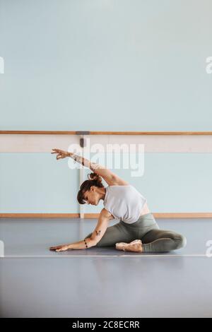 Ballerina faisant des exercices d'étirement sur le sol en studio Banque D'Images