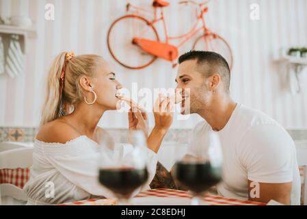 Un jeune couple aimant se nourrissant de pizza les uns les autres au restaurant Banque D'Images