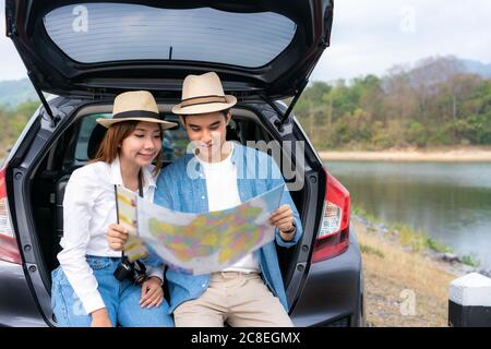 Portrait d'un couple asiatique assis en voiture et contenant des cartes à la recherche d'une destination suivante pour voyager pendant des vacances ensemble en vacances. Bonne romantique TI Banque D'Images