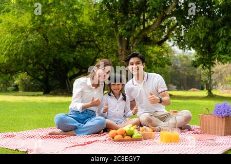 Famille des adolescents asiatiques bonne vacances pique-nique moment dans le parc avec père, mère et fille regardant la caméra et sourire à heureux passer des vacances à Banque D'Images