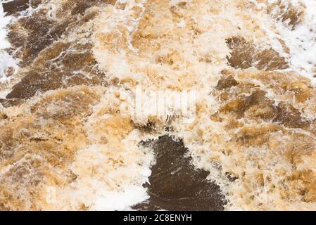 Eau brute de rivière inondée qui coule sauvage à travers la nature, courants forts, tourbillons, mousse et rochers comme toile de fond et espace de copie. Banque D'Images