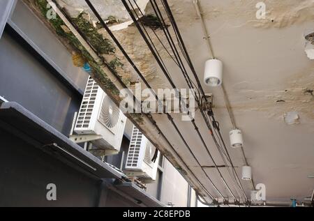 Une attention sélective sur les lignes électriques 3 fils 4 phases se trouvent sous le plafond de la couche de peinture écaillée à l'extérieur d'un bâtiment, vue à angle bas Banque D'Images