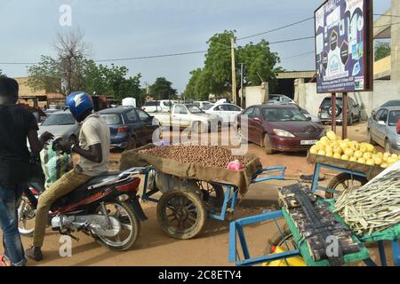 Poussettes de marchandises à vendre et voitures garées au bord d'une intersection très fréquentée à Niamey, Niger, Afrique Banque D'Images