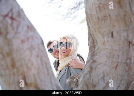 Le couple arabe pose dans un environnement ensoleillé entre les troncs d'arbre Banque D'Images