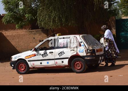 Une femme bien habillée à côté d'un taxi décoré à Niamey, Niger Banque D'Images