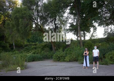 Un couple masqué regarde le coucher du soleil sur la plage de la rivière Willamette dans un parc municipal du lac Oswego le jeudi 22 juillet 2020, pendant la pandémie du coronavirus. Banque D'Images