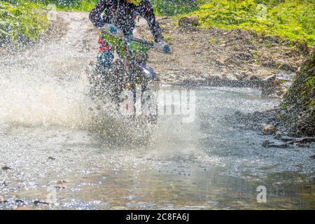 Journée d'été ensoleillée et forêt de streem. Beaucoup de projections d'eau masque une moto endoro Banque D'Images