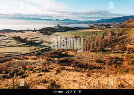 Le soleil s'élève sur des terres fertiles et des arbres d'automne au lac Wanaka, vu de Roys Peak Track, en Nouvelle-Zélande Banque D'Images