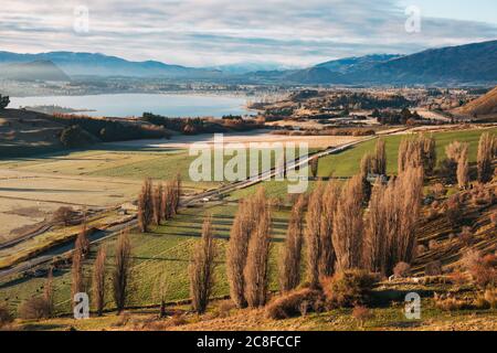 Le soleil s'élève sur des terres fertiles et des arbres d'automne au lac Wanaka, vu de Roys Peak Track, en Nouvelle-Zélande Banque D'Images