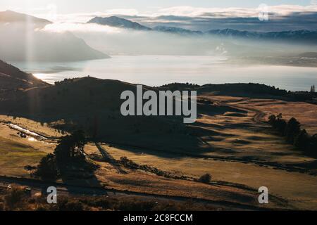 Le soleil s'élève sur des terres fertiles et des arbres d'automne au lac Wanaka, vu de Roys Peak Track, en Nouvelle-Zélande Banque D'Images