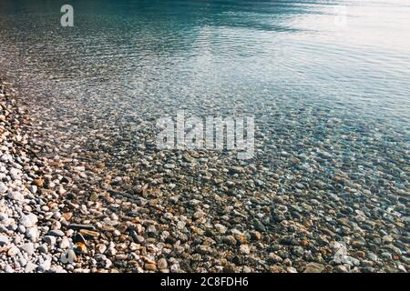 L'eau cristalline recrée la lumière lorsqu'elle se lave au-dessus des cailloux sur la rive et lacédée du lac Hawea, en Nouvelle-Zélande Banque D'Images