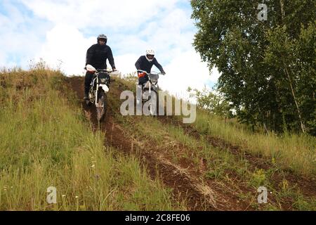 Motocyclistes actifs dans des casques de descente de moto tout en développant leurs compétences sur la piste tout-terrain Banque D'Images