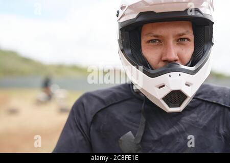 Portrait d'un jeune cycliste sérieux, casque blanc, sur piste tout-terrain Banque D'Images