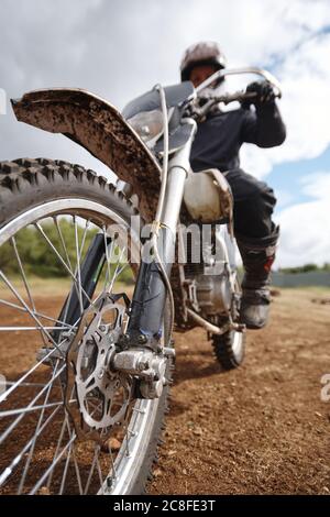 Concentrez-vous sur la roue de moto sale sur la piste tout-terrain, le motocycliste prêt pour la course Banque D'Images