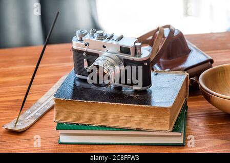 Ancien appareil photo vintage et livres avec bâton d'encens à l'ancienne table en bois dans le jardin Banque D'Images