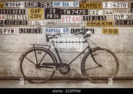 Ancienne bicyclette devant une ancienne porte d'usine avec plaques d'immatriculation