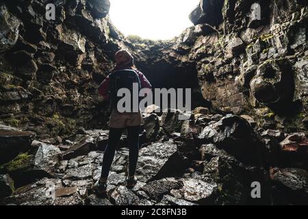 Une femme voyageur explore le tunnel de lave en Islande.