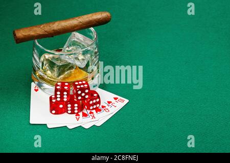 verre de whisky avec cigare, cartes à jouer et dés sur feutre vert Banque D'Images