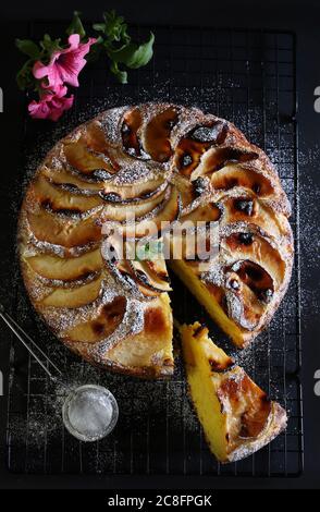 Tarte aux pommes cuite au four saupoudrée de sucre en poudre sur fond de bois noir. Banque D'Images