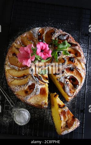 Tarte aux pommes cuite au four saupoudrée de sucre en poudre sur fond de bois noir. Banque D'Images