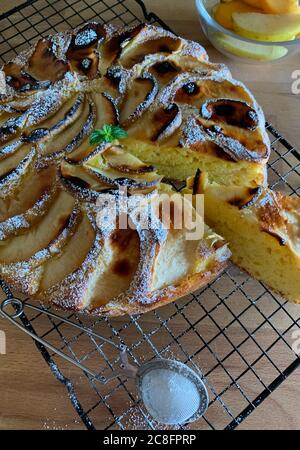 Tarte aux pommes maison arrosée de sucre en poudre, décorée de feuilles de menthe sur une table en bois. Vue de dessus. Banque D'Images