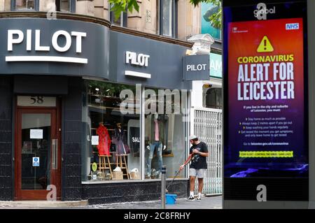 Leicester, Leicestershire, Royaume-Uni. 24 juillet 2020. Un travailleur nettoie la fenêtre d'un magasin de vêtements Pilot après que les restrictions locales de confinement du coronavirus ont été assouplies. Les magasins non essentiels peuvent rouvrir dans la zone verrouillée, même si le gouvernement a déclaré que tous les déplacements à l'intérieur, à l'extérieur et à l'intérieur de la ville sont toujours interdits. Credit Darren Staples/Alay Live News. Banque D'Images