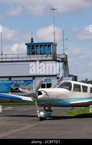 Avion léger stationné sur un tarmac avec tour de contrôle derrière. Aéroport de Wolverhampton Halfpenny Green. Staffordshire. ROYAUME-UNI Banque D'Images