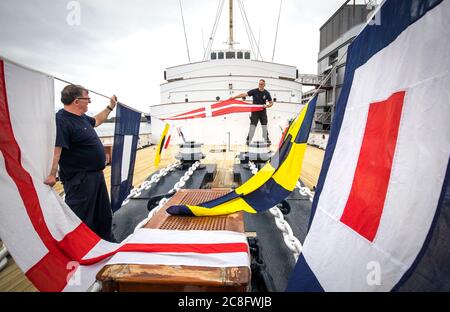 Tony Smith (à gauche) et Rab McAulay, de l'équipe d'entretien, lèvent les drapeaux habrtés sur le yacht royal Britannia pour marquer la réouverture de l'attraction touristique d'Édimbourg aux membres du public le lundi 27 juillet. Banque D'Images