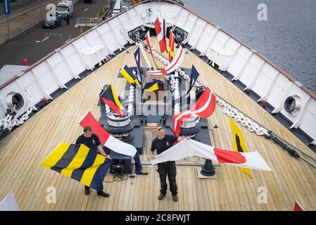 Tony Smith (à gauche) et Rab McAulay, de l'équipe d'entretien, lèvent les drapeaux habrtés sur le yacht royal Britannia pour marquer la réouverture de l'attraction touristique d'Édimbourg aux membres du public le lundi 27 juillet. Banque D'Images