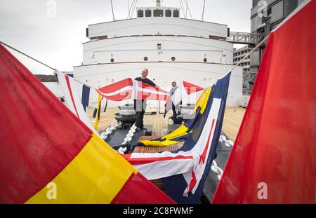 Rab McAulay (à gauche) et Tony Smith, de l'équipe d'entretien, lèvent les drapeaux habrisés sur le yacht royal Britannia pour marquer la réouverture de l'attraction touristique d'Édimbourg aux membres du public le lundi 27 juillet. Banque D'Images