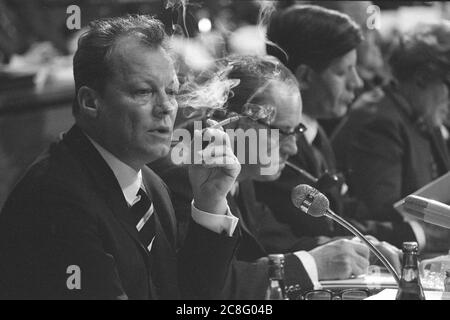 Nuremberg, Allemagne. 21 juillet 2020. Willy BRANDT, SPD, président du SPD et chancelier fédéral, siège dans le plénum et fume une cigarette, derrière elle Herbert WEHNER avec pipe et Helmut SCHMIDT, à la conférence du parti SPD 1968 à Nuernberg, le 18 mars 1968, Â | usage dans le monde crédit: dpa/Alay Live News Banque D'Images