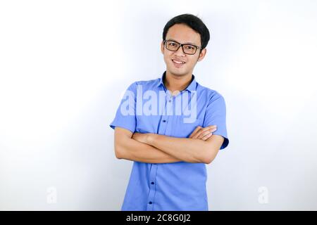 Portrait d'un jeune asiatique vêtu à la mode, debout avec confiance avec ses bras croisés contre un mur gris. Banque D'Images