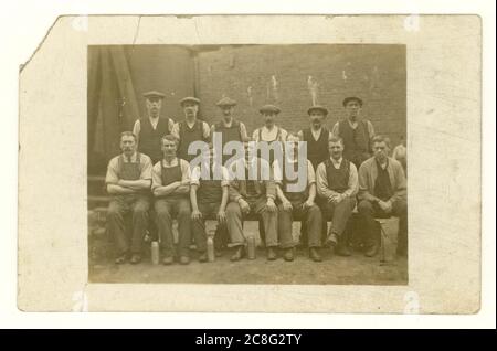 Début 1900 carte postale des hommes de la classe ouvrière à l'extérieur dans la cour, portant des bouchons plats, avec des flacons, vers 1907, Royaume-Uni Banque D'Images