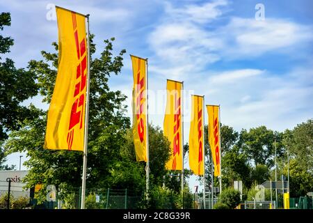 Drapeaux portant le logo DHL devant le centre de distribution de colis du groupe Deutsche Post DHL à Berlin, en Allemagne. Banque D'Images