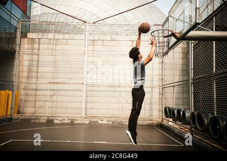 jeune homme asiatique adulte joueur de basket-ball essayant une dunk sur un terrain extérieur Banque D'Images