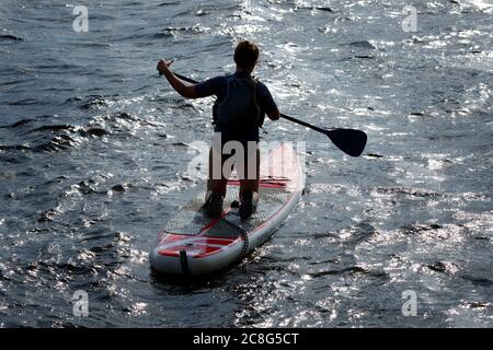 Jeune femme s'agenouillant sur une planche à aubes au coucher du soleil. Banque D'Images