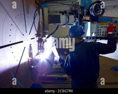 Homme portant un masque de soudage travaillant dans une usine d'acier. Banque D'Images