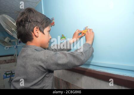 QUETTA, BALOUTCHISTAN, PAKISTAN. 24 au 2020 juillet : un patient enfant collant des grévistes sur le mur pendant une activité de décoration de paroisse avec des patients enfants. Organisé b Banque D'Images