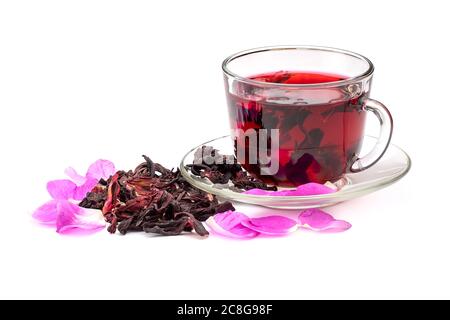 Thé hibiscus dans une tasse de verre parmi les pétales de rose et les pétales secs isolés sur fond blanc. Banque D'Images