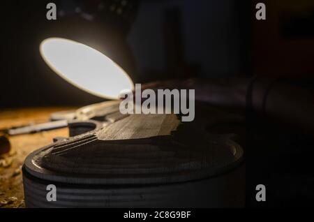 Jeune femme belle, Luthier, sculptant une table de violon avec des outils dans un atelier de Cremona Banque D'Images